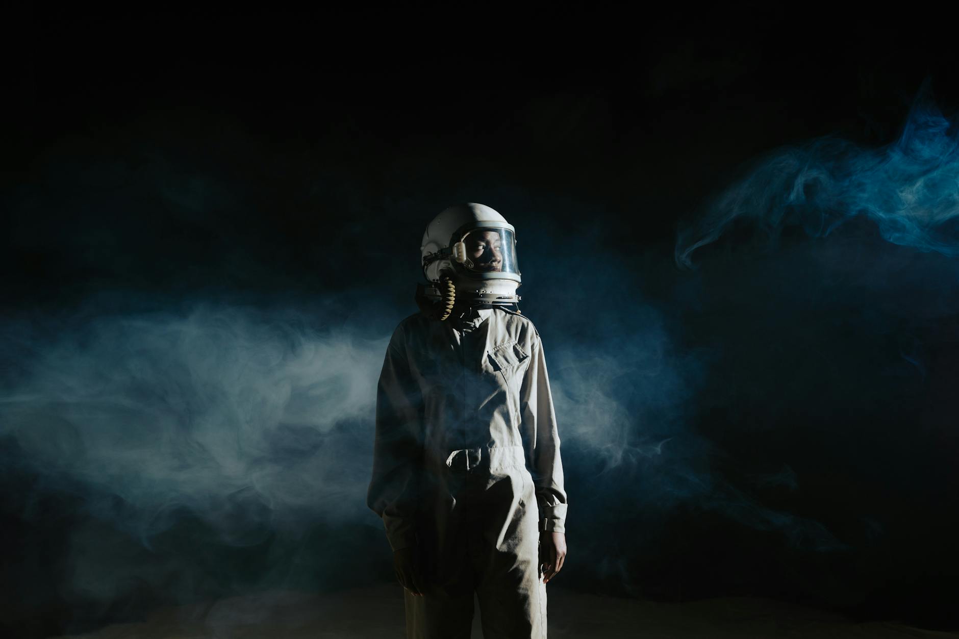 person in gray space suit standing with smoke on background